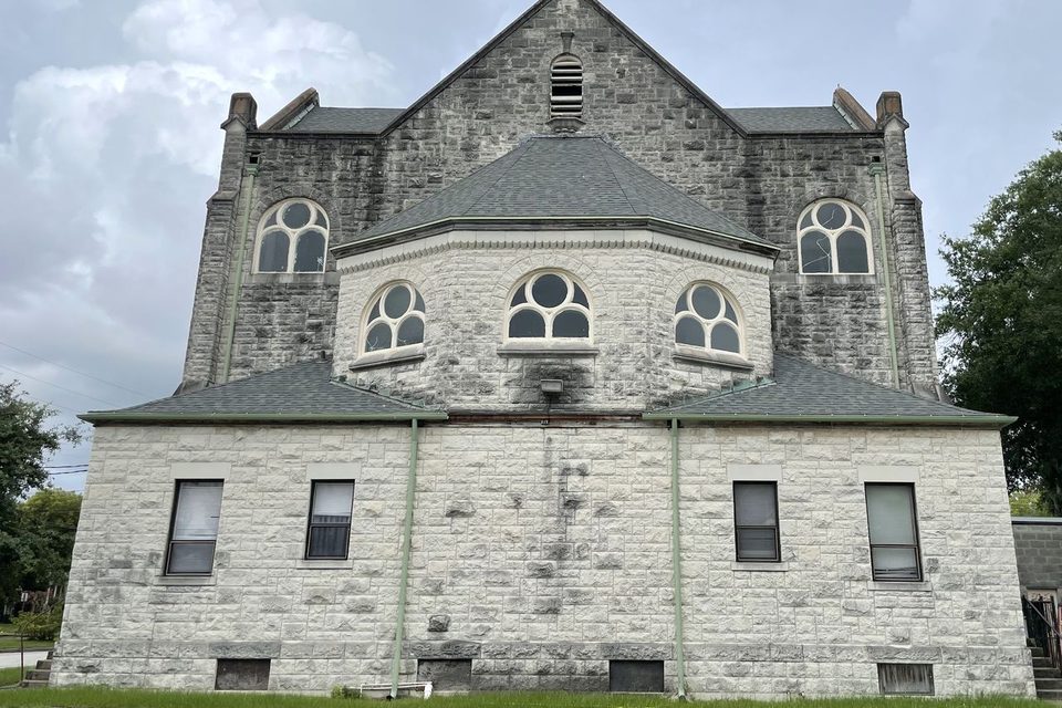 The stone wall of a church streaked black with mildew