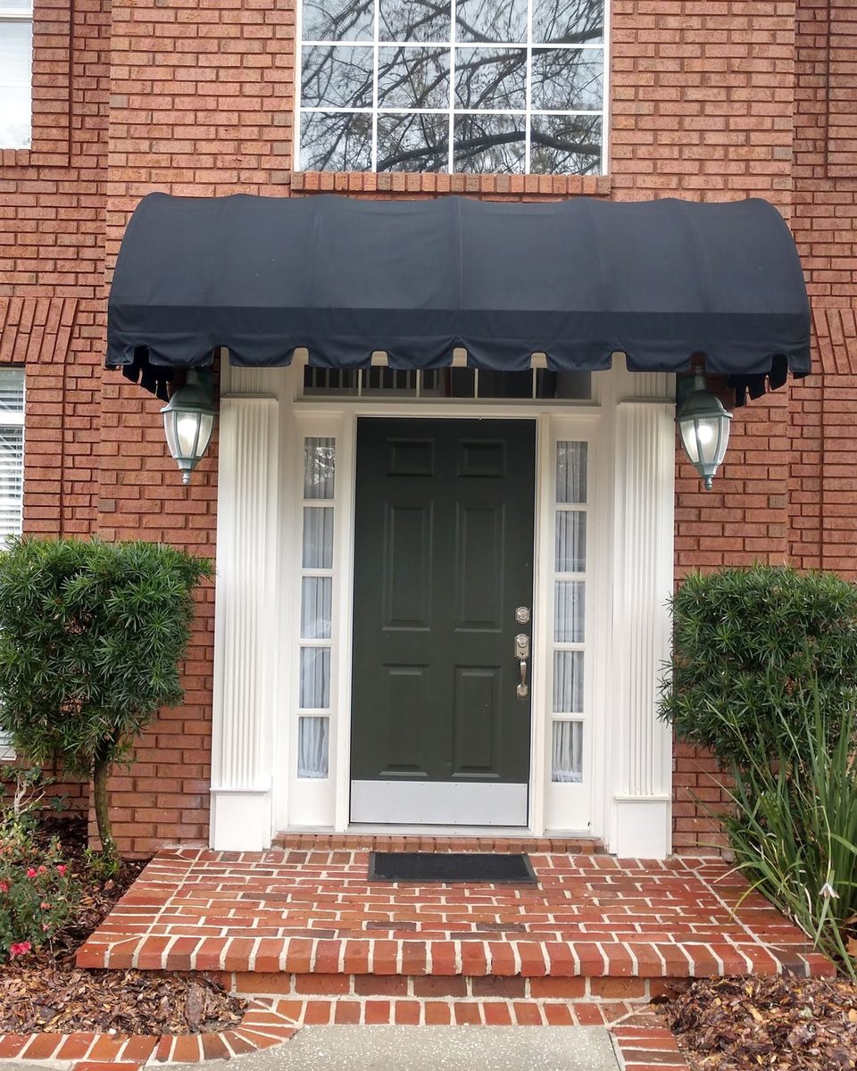 The same front entry after the wash: the awning clean and dark, the brick steps red again