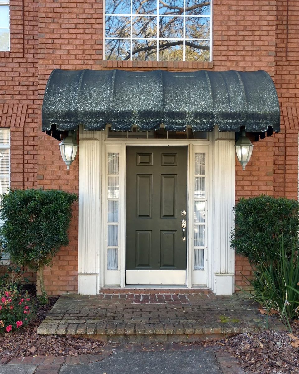 A brick front entry before a house wash: a green, stained awning and dull brick steps