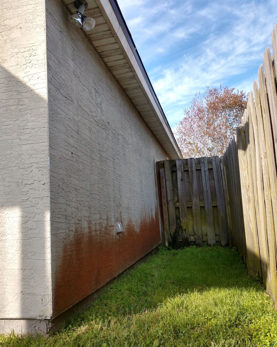 A stucco wall stained red and brown along the bottom