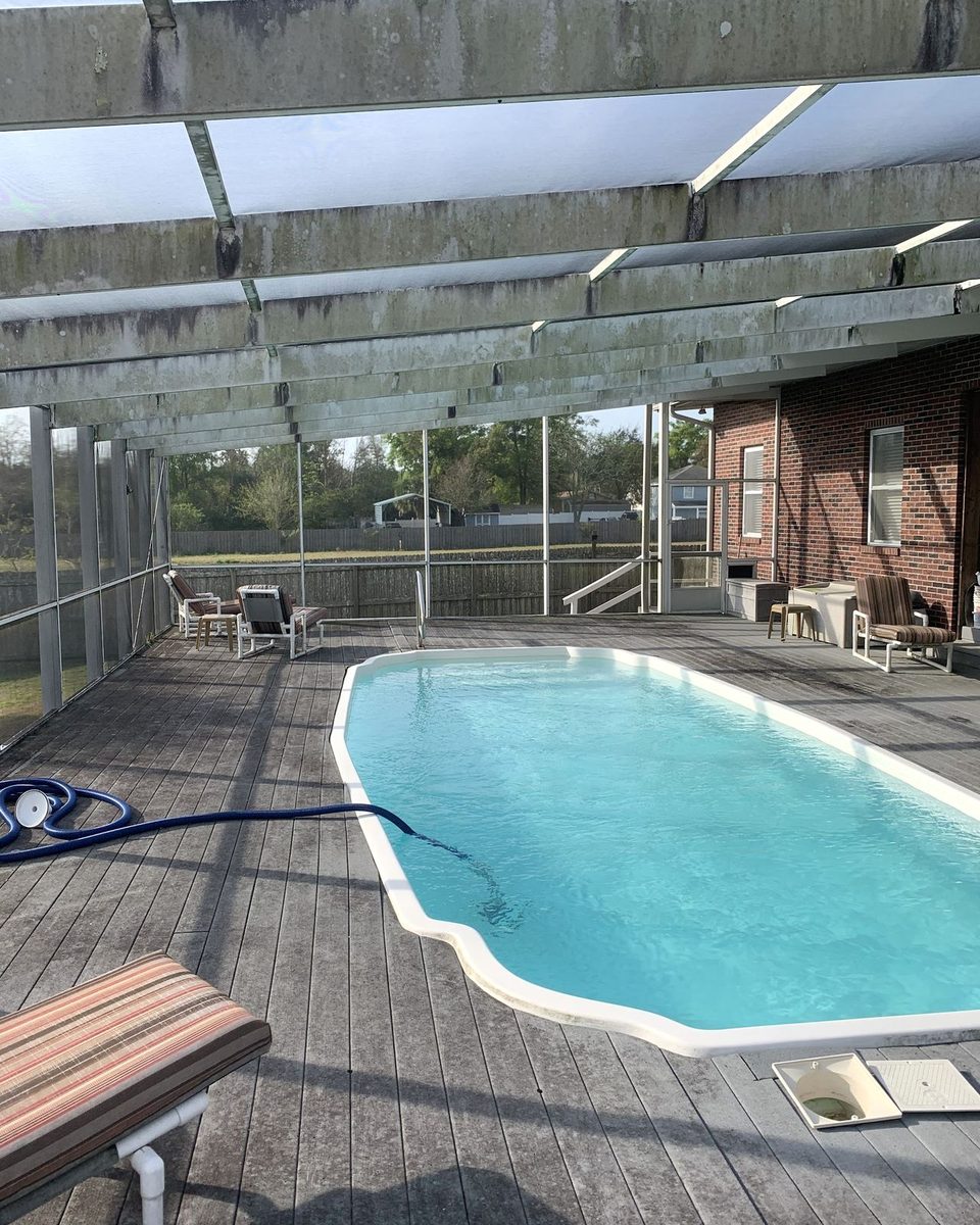 A pool screen enclosure with the frames black with mildew