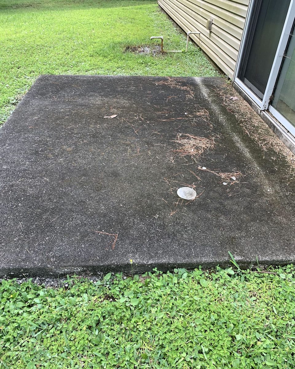 A concrete slab beside a house, black with mildew