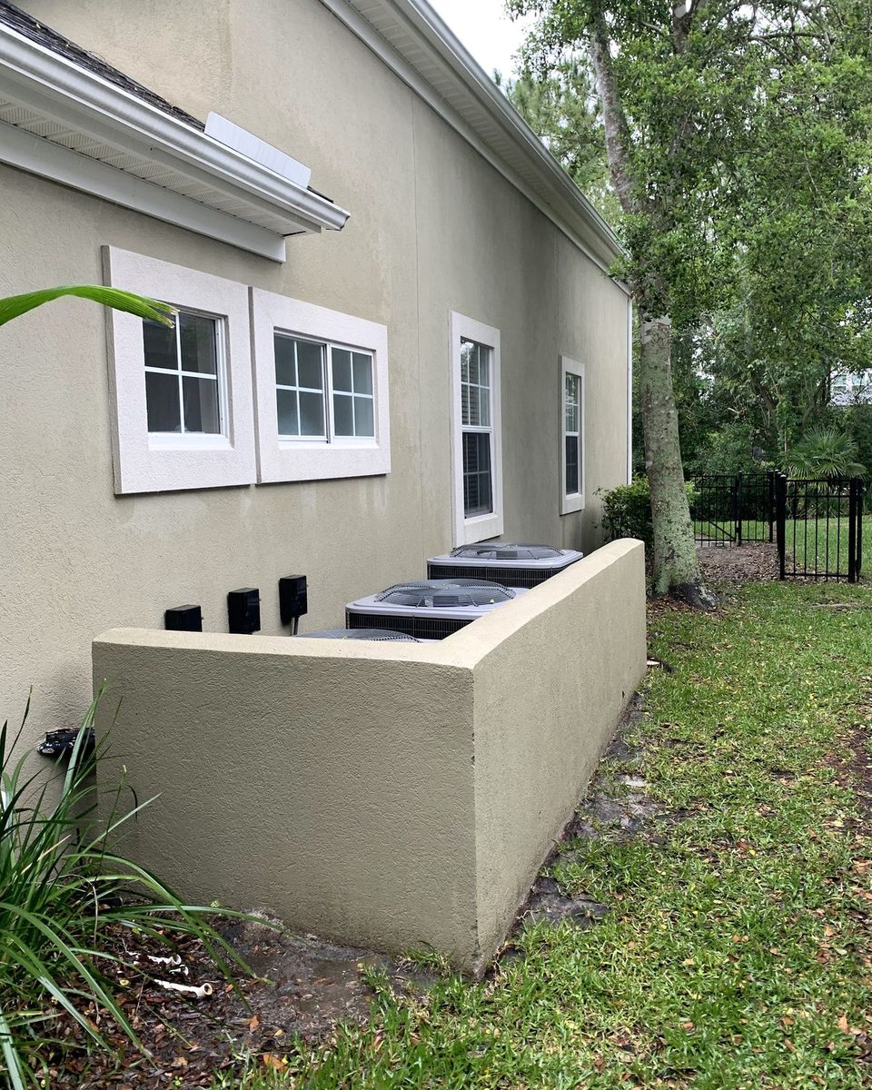 The same wall and AC enclosure after a soft wash