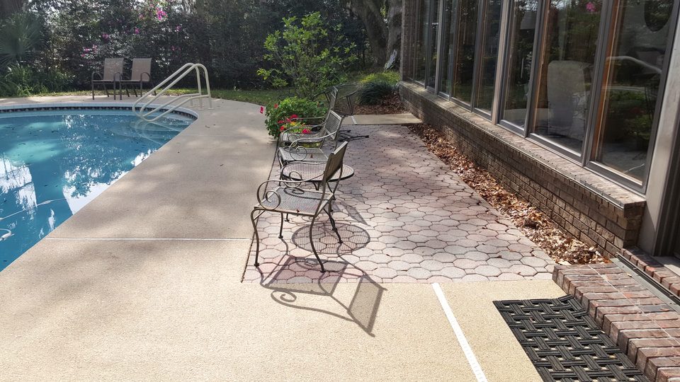 A concrete pool deck and paver patio beside a pool after cleaning