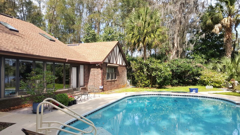 The back of a brick house and its pool deck after a wash