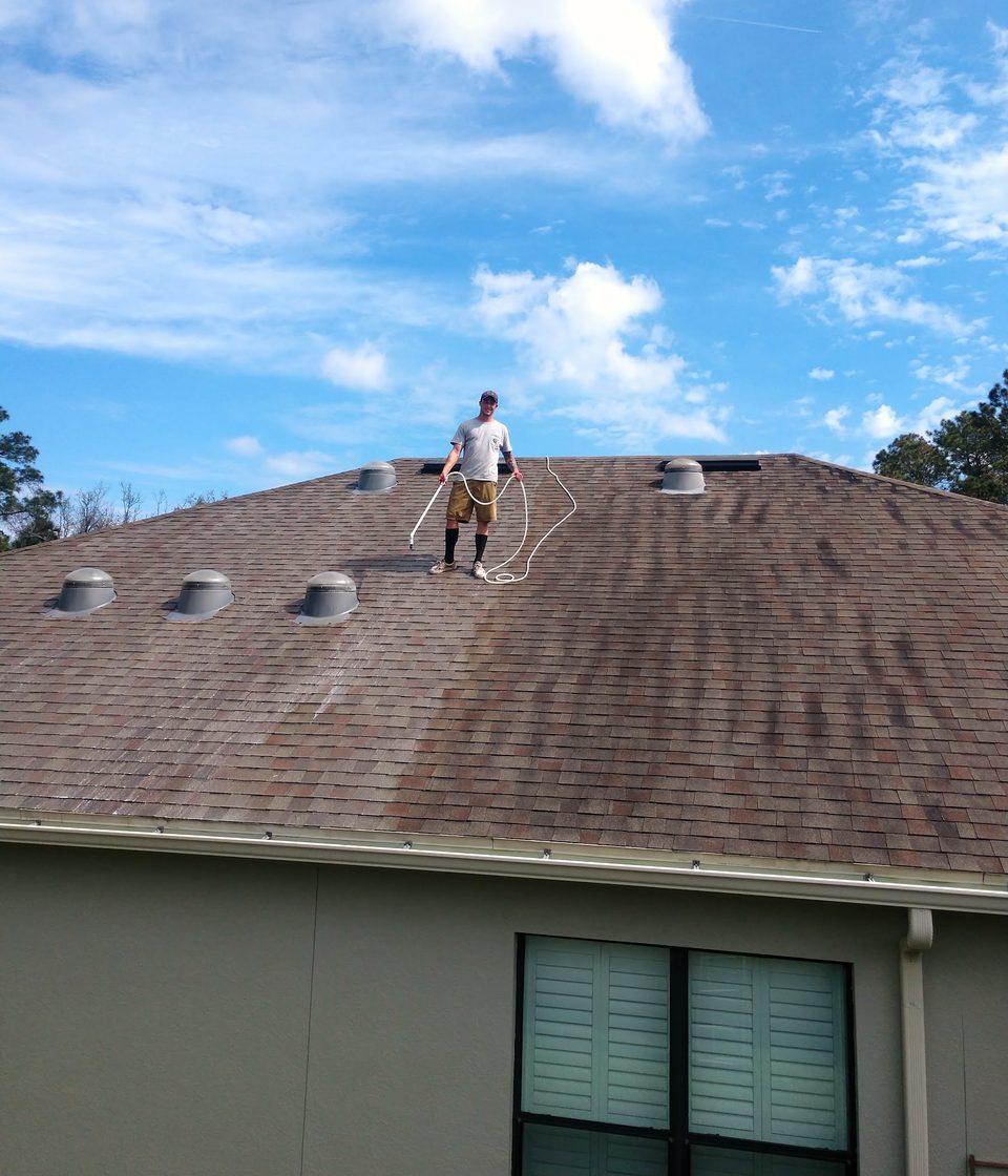A Bullseye technician on a shingle roof during a soft wash